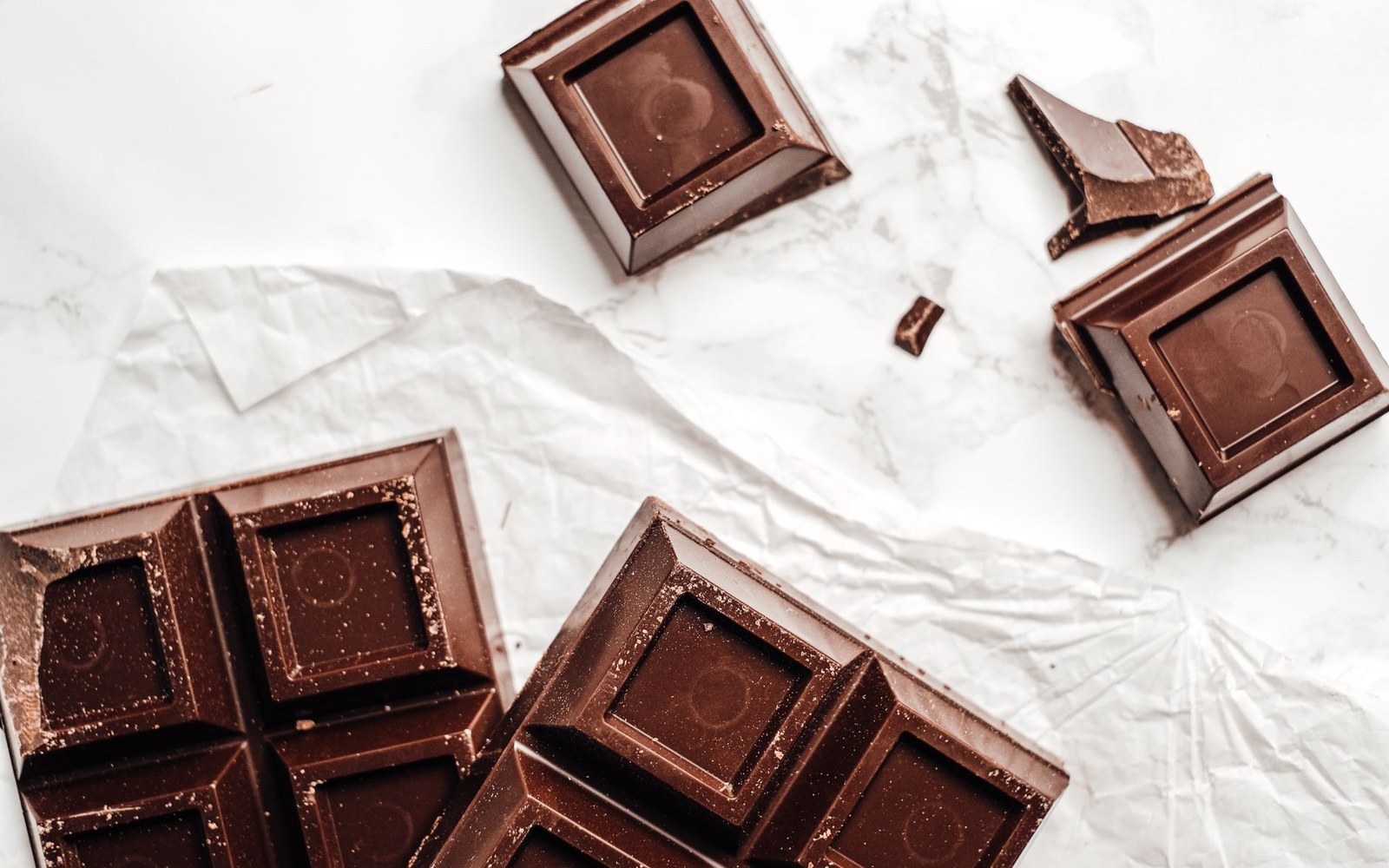A bloomed chocolate bar shot very close, the white fat-bloom streaks across the dark surface read as texture rather than damage