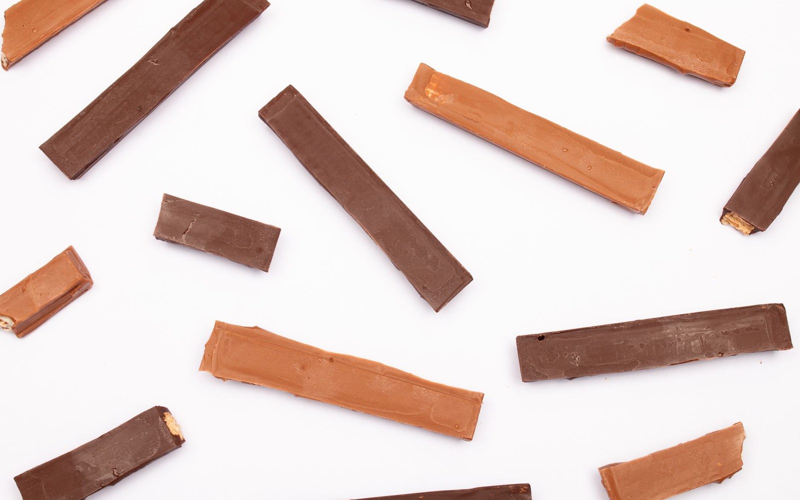 Chocolate fingers scattered on a white ground, several of them noticeably paler than the rest