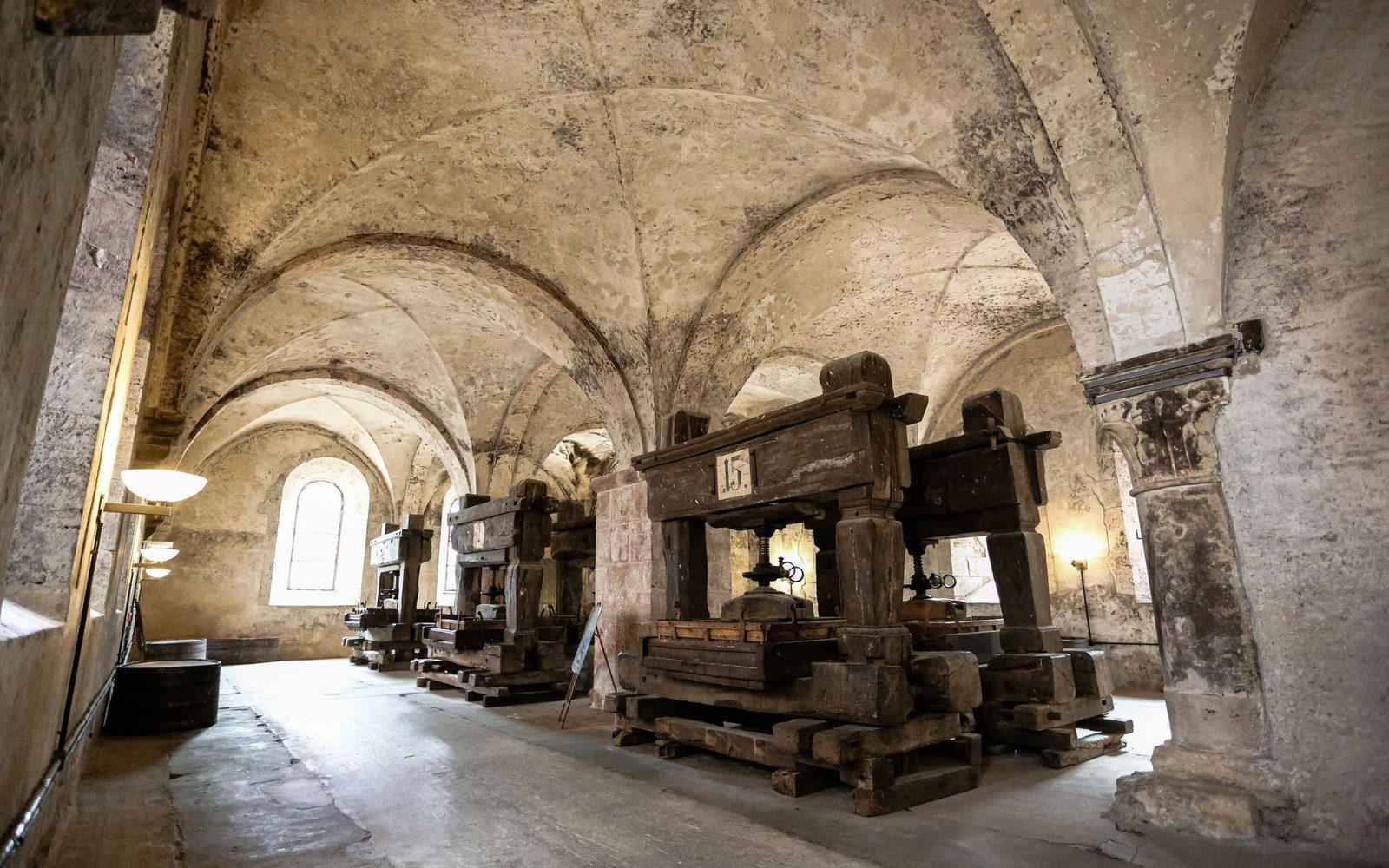 A vaulted stone hall with rows of large wooden screw presses