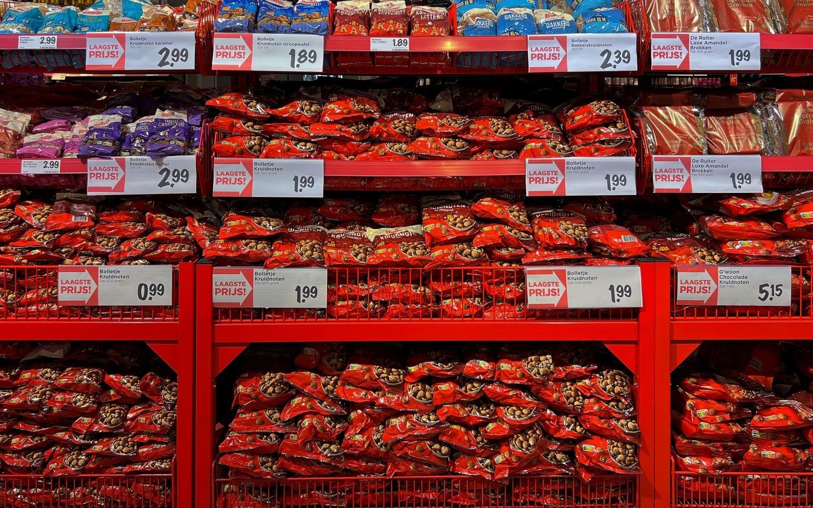 Red supermarket shelving packed with bagged confectionery under printed lowest-price labels