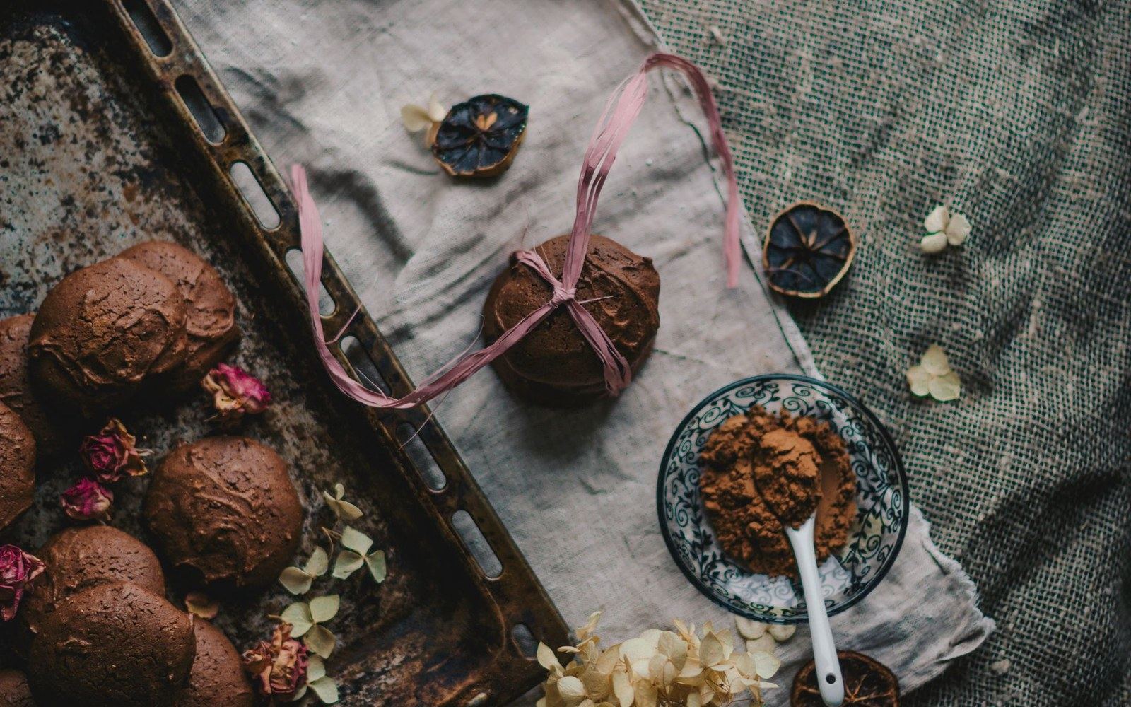 Cocoa-dusted truffles on linen beside a small bowl of cocoa powder and a spoon