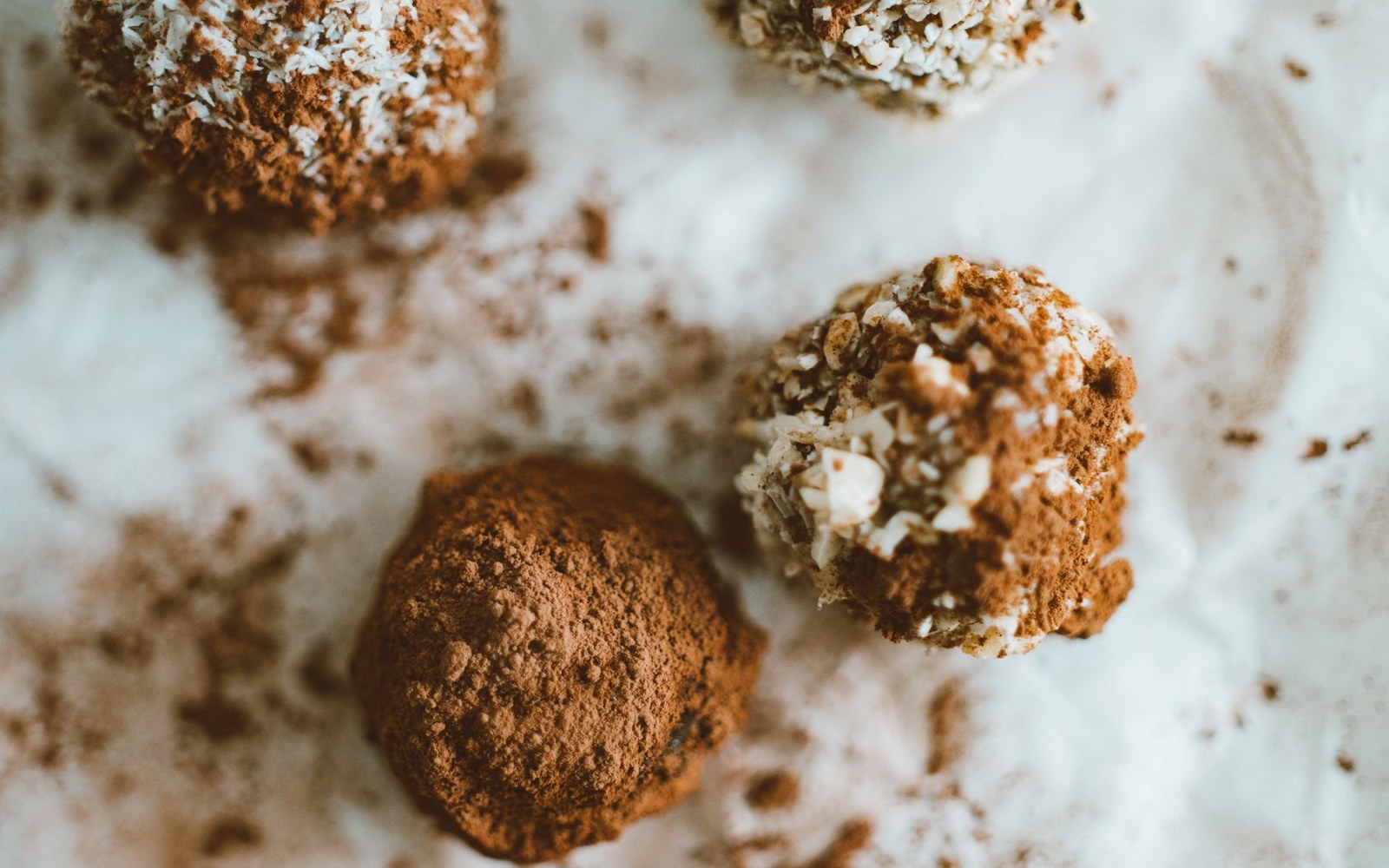 A tray of hand-rolled chocolate truffles dusted with dark cocoa powder, close and even, shot on a dark slate surface